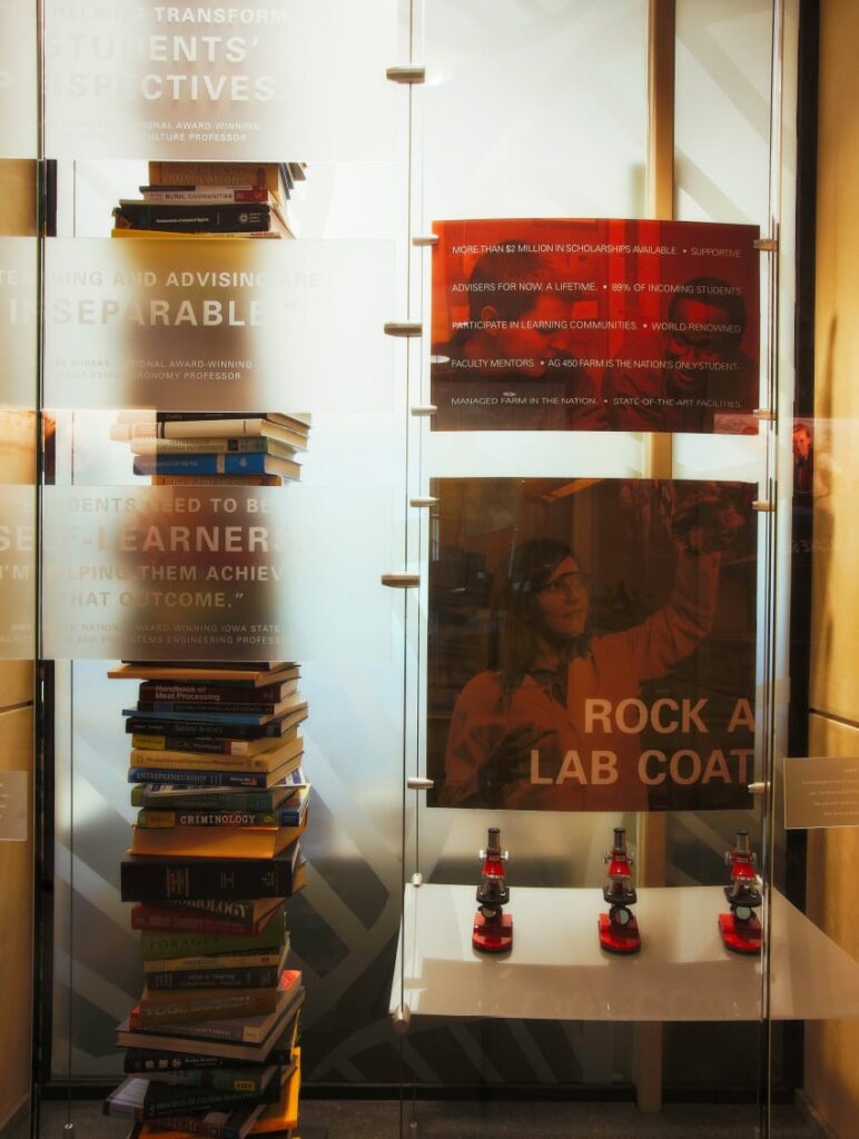 Glass display cases filled with books, equipment, and artwork featuring branded photography and typography in ISU's College of Agriculture and Life Sciences.