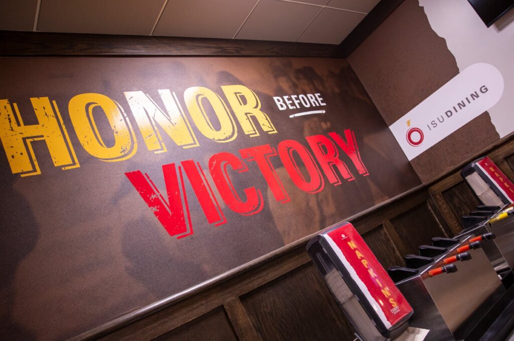 Wall graphics designed for ISU Dining's Clyde's Gastro Diner, with typography declaring, "Honor before victory."