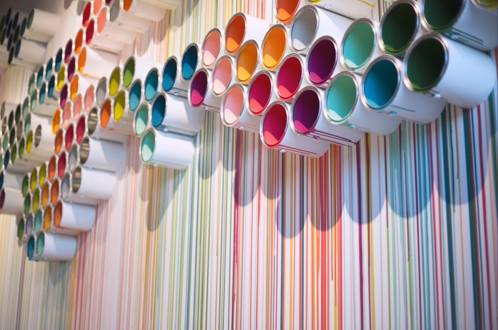 Art installation in the Flying Hippo office's entrance, featuring colorful paint buckets arranged near the ceiling and paint dripping all the way to the floor.