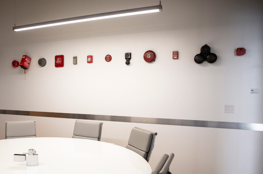 Conference room in the Flying Hippo office, featuring an art installation showcasing numerous fire alarms.