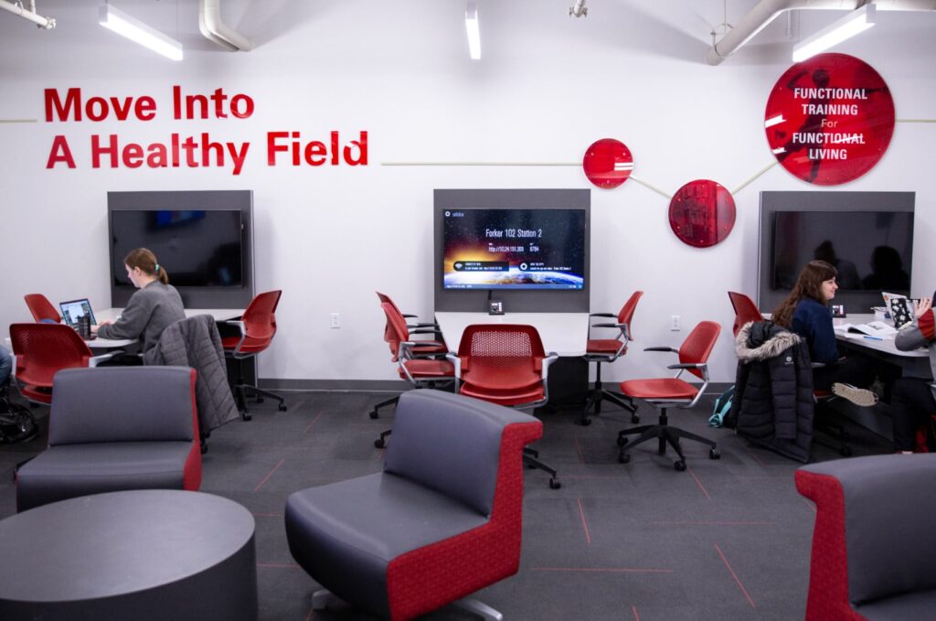 Environmental design for ISU's Department of Kinesiology, featuring 3D letters stating, "Move into a healthy field," and wall art around a student lounge area.