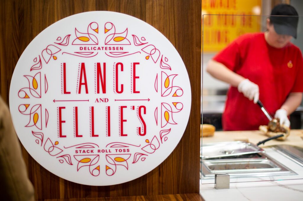 Lance and Ellie's Delicatessen logo printed on a sign beside the restaurant counter.