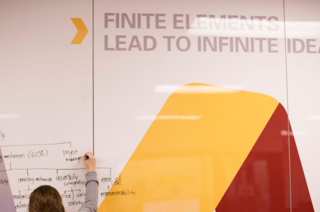 Detail of the dry erase board walls in The Mine, ISU's Department of Mechanical Engineering basement labs. Bold typography declares, "Finite elements lead to infinite ideas."