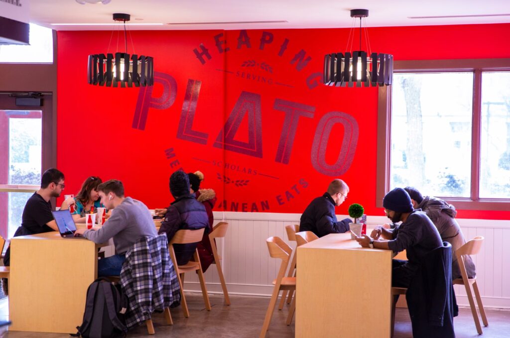 The "Heaping Plato" logo printed in a massive floor-to-ceiling wall graphic between windows in the restaurant.