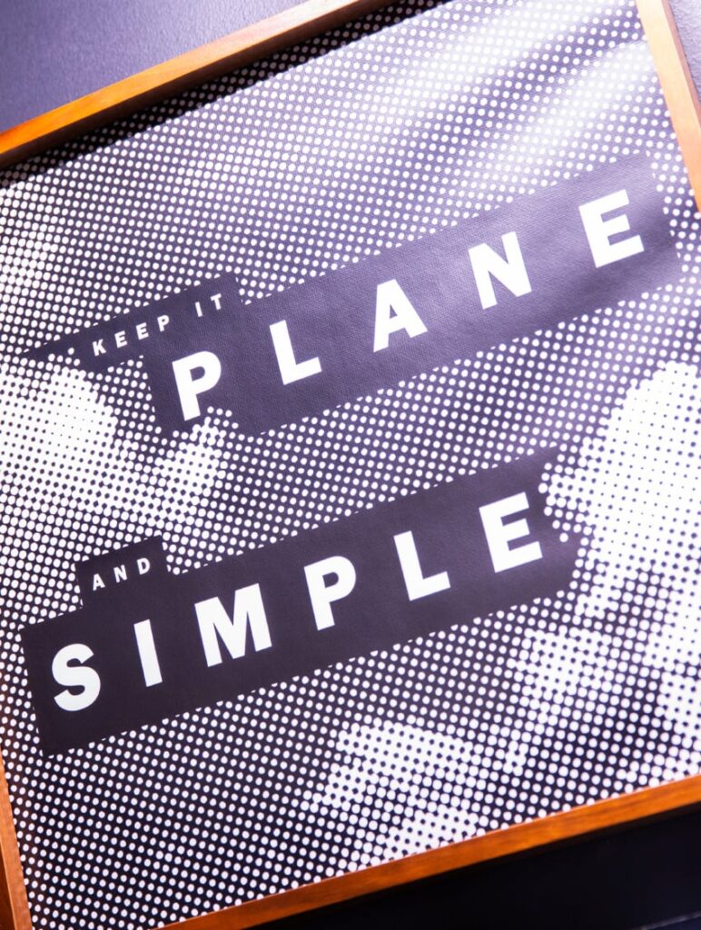 Graphic detail framed on The Roasterie wall, with bold typography declaring, Keep it plane and simple."