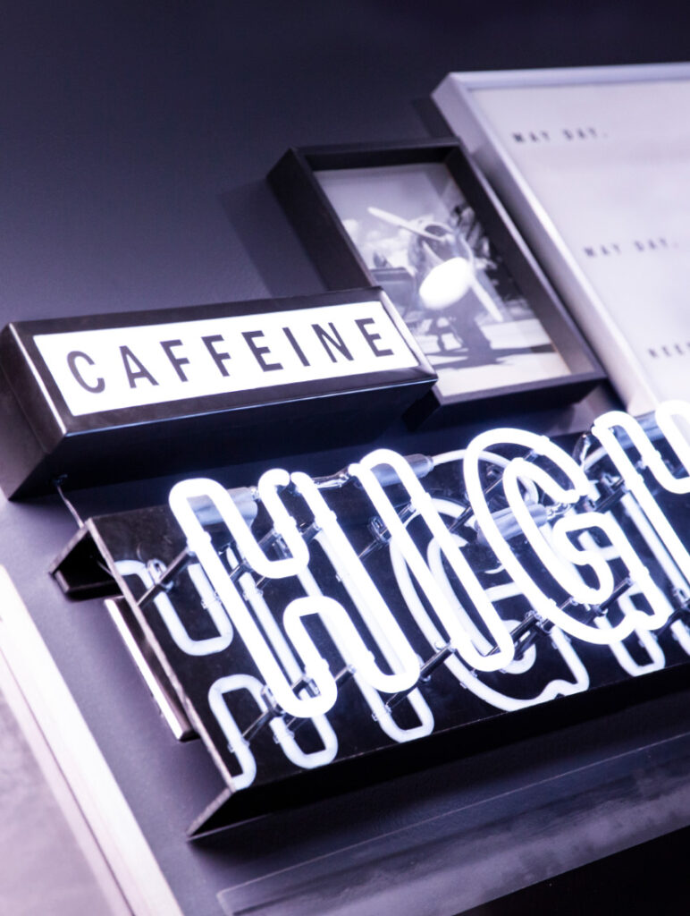 Detail of the wall art at The Roasterie, including a white neon sign declaring, "High."