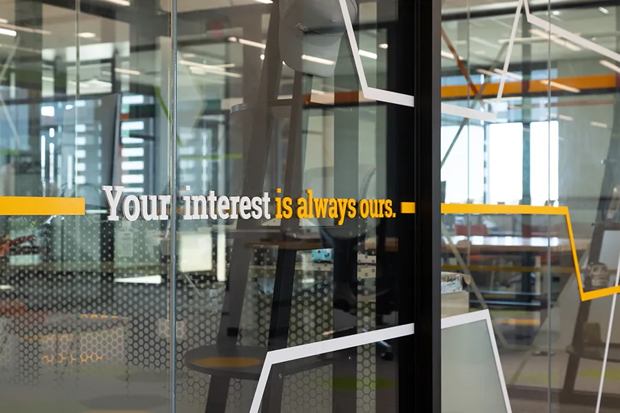 Detail of decal lettering on a cubicle window at Farmer's State Bank, featuring the tagline, "Your interest is always ours."