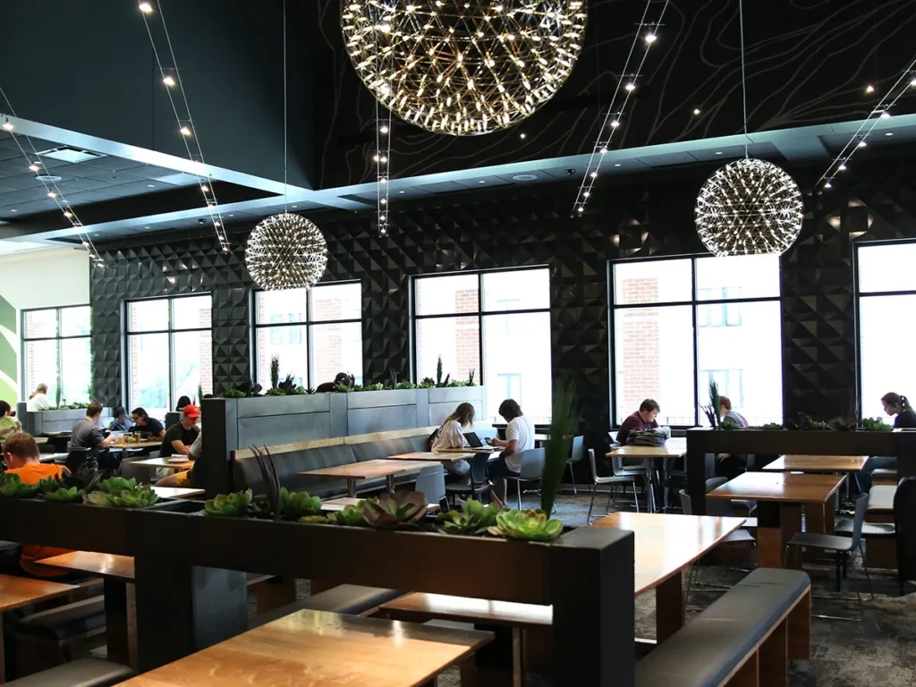 Photo of the Union Drive Marketplace "Night Room" at Iowa State University, with students seated at tables under dandelion chandeliers.