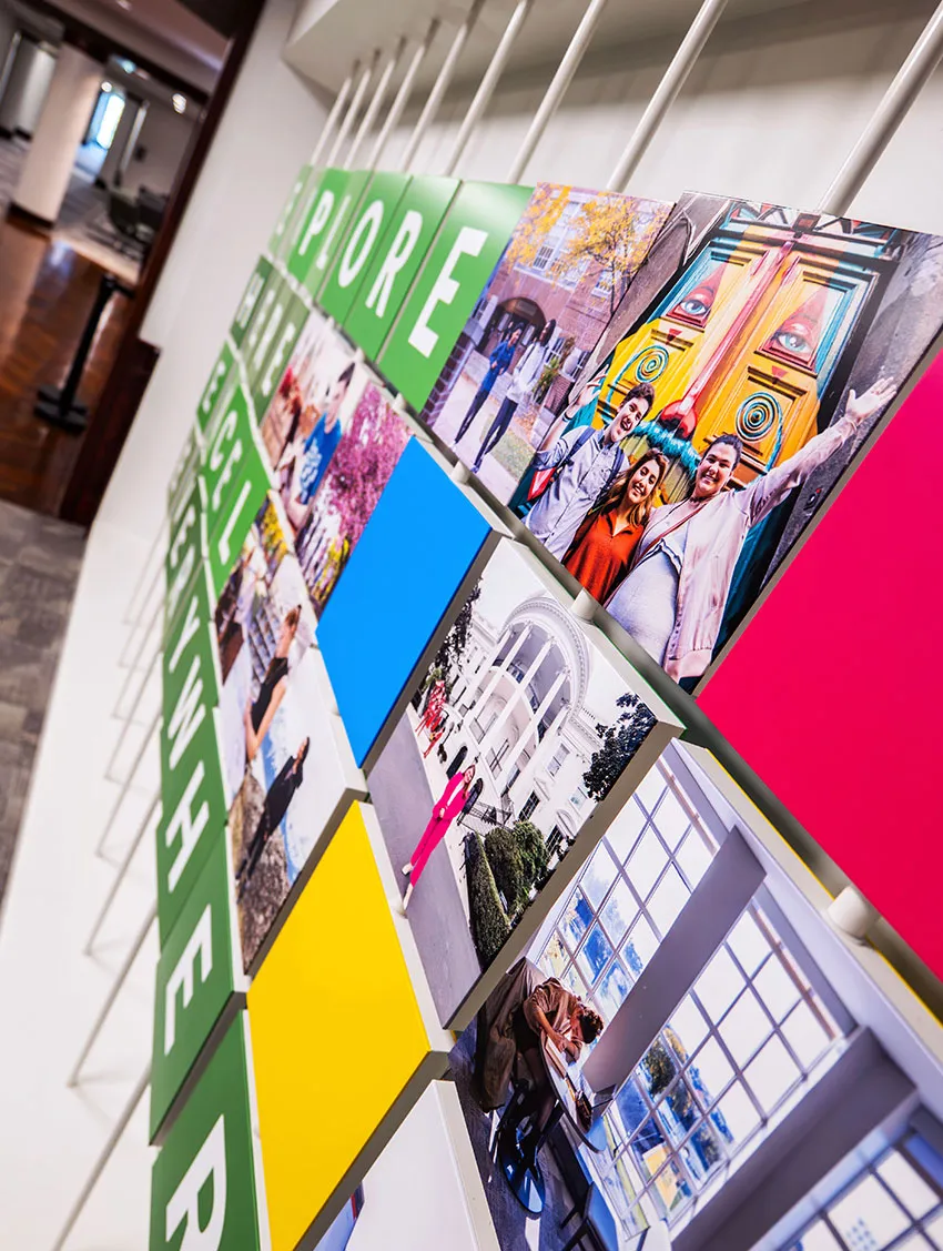 Colorful wall display featuring photos, green and yellow panels, and the word EXPLORE in artistic arrangement.