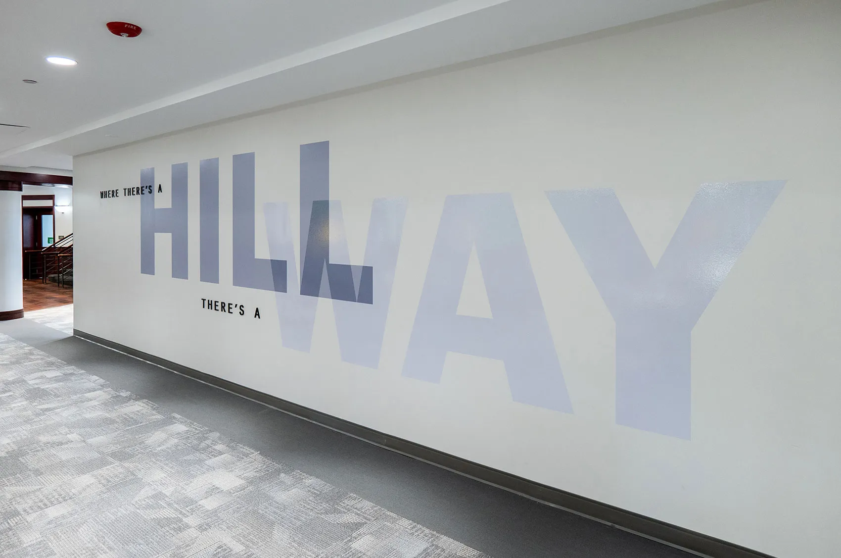 Hallway with motivational slogan Where there's a Hill, there's a Way on the wall in modern office space.